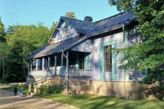 Vaalean sininen kartano rakennus kesällä.